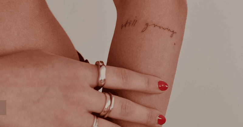 Still growing written in small, spaced handwriting on an arm