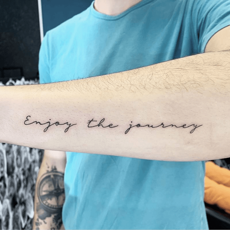 Enjoy the journey written in clear, widely spaced cursive along a forearm